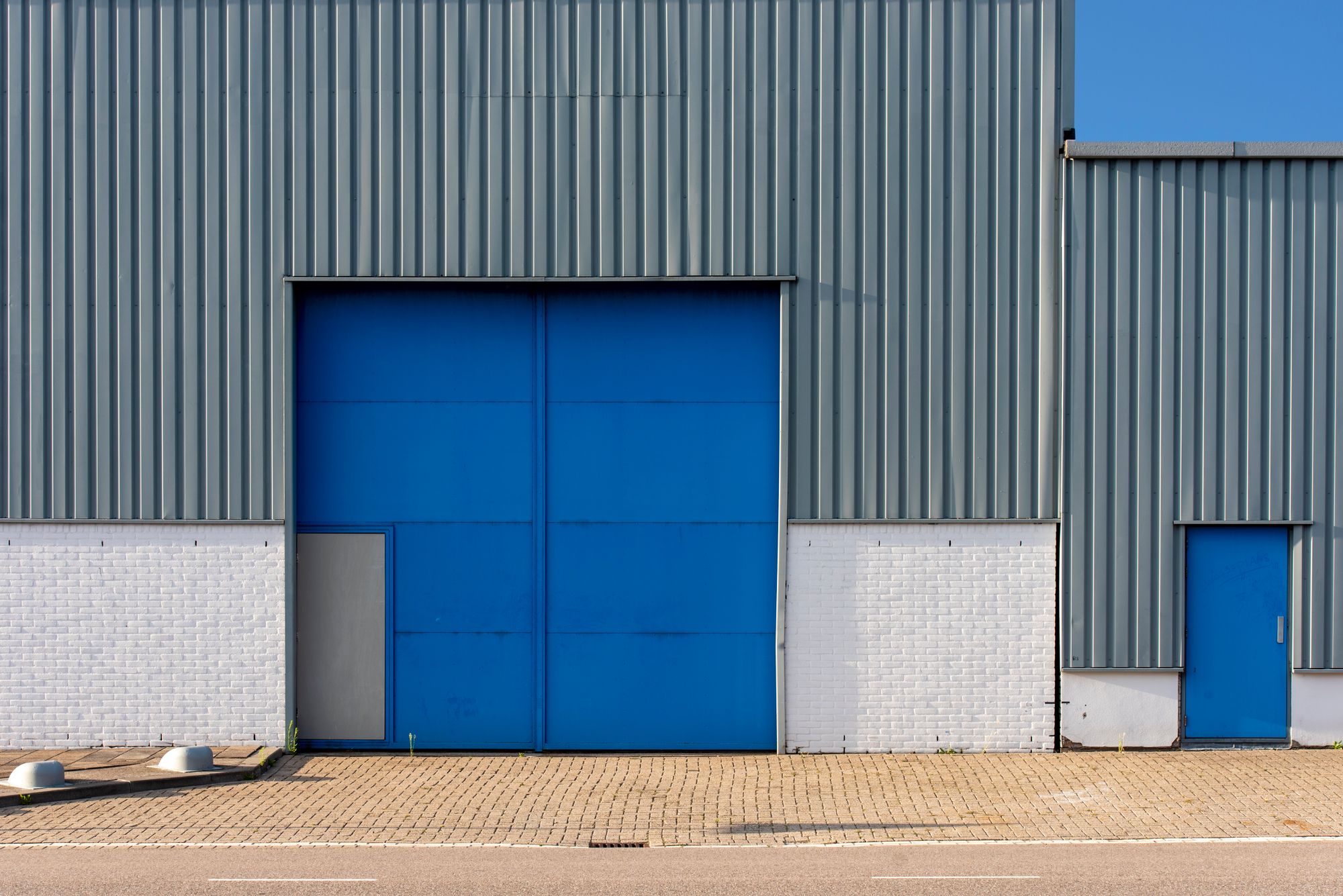 Illustrative photograph of a metal warehouse facade with a blue door. Not a 419 project.